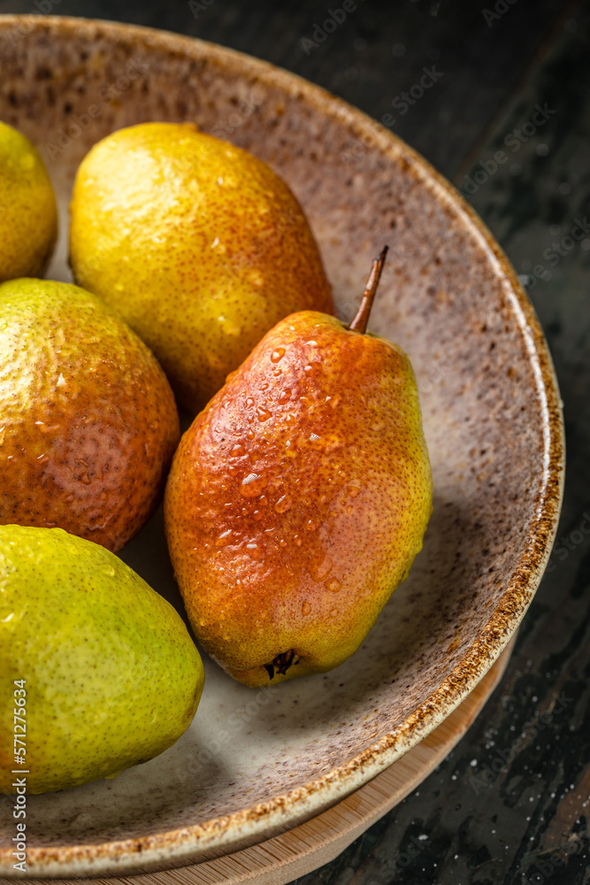 ripe pears in a bowl on a wooden background