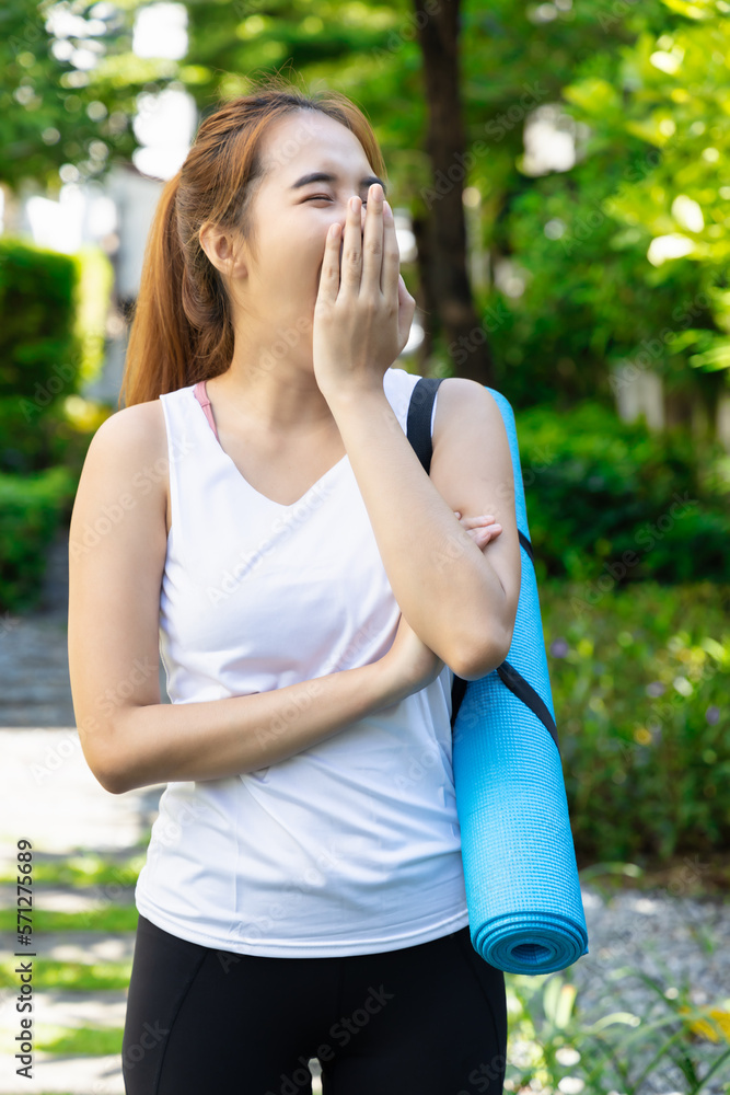 Tired and sleepy asian fitness woman yawning, carrying yoga mat without proper sleep Tired and sleepy asian fitness woman yawning, carrying yoga mat without proper sleep