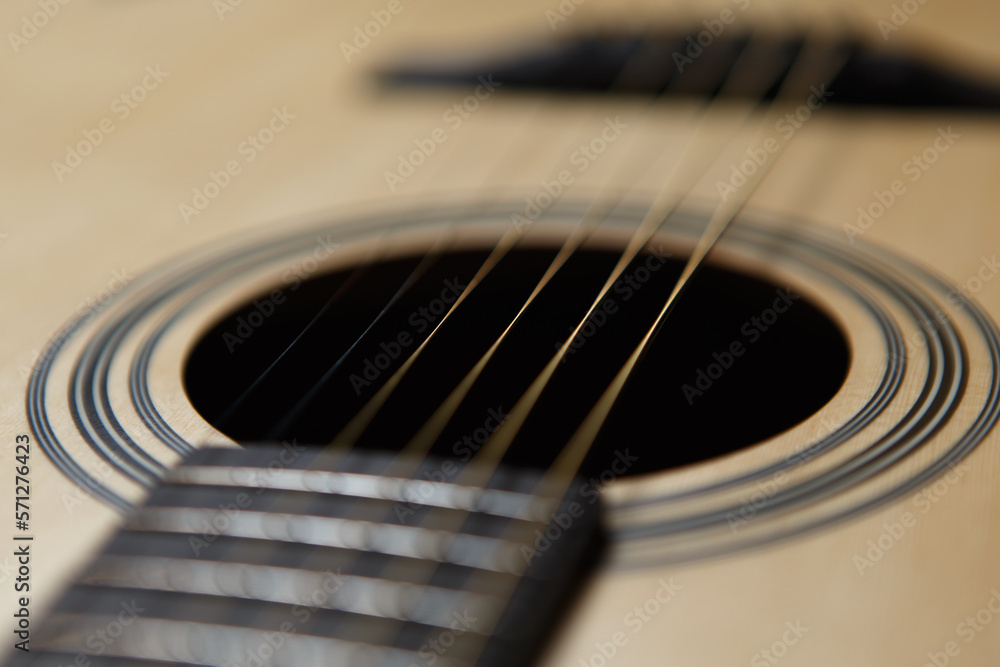 Six string acoustic guitar in close up. Focus on metal strings and hole in sound board Six string acoustic guitar in close up. Focus on metal strings and hole in sound board