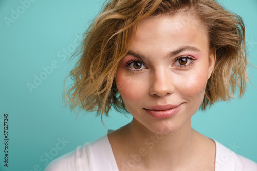 Beautiful woman smiling at camera while posing isolated over blue background