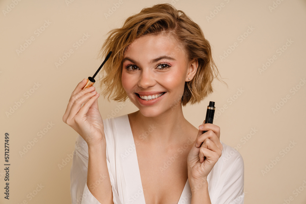 Obraz premium Young cheerful woman posing with mascara isolated