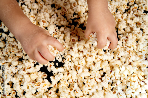 Children's hands are picking up popcorn. Flat lay . The concept of a birthday, party, holiday, home leisure. Copy space for your product. Popcorn texture or background.