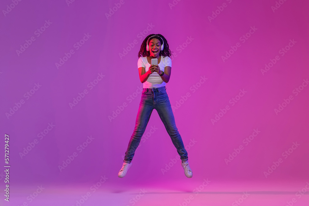 Joyful Black Woman With Smartphone In Hands Jumping Over Purple Gradient Background, Joyful Black Woman With Smartphone In Hands Jumping Over Purple Gradient Background,
