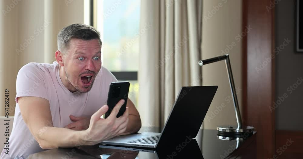 Adult happy businessman rejoices while reading great news on smartphone Adult happy businessman rejoices while reading great news on smartphone