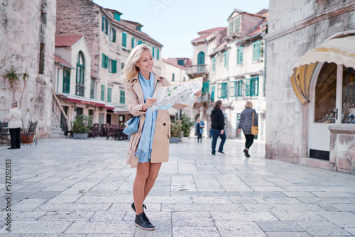 Travel and active lifestyle concept. Young traveller woman walking on old town holding tourist map.