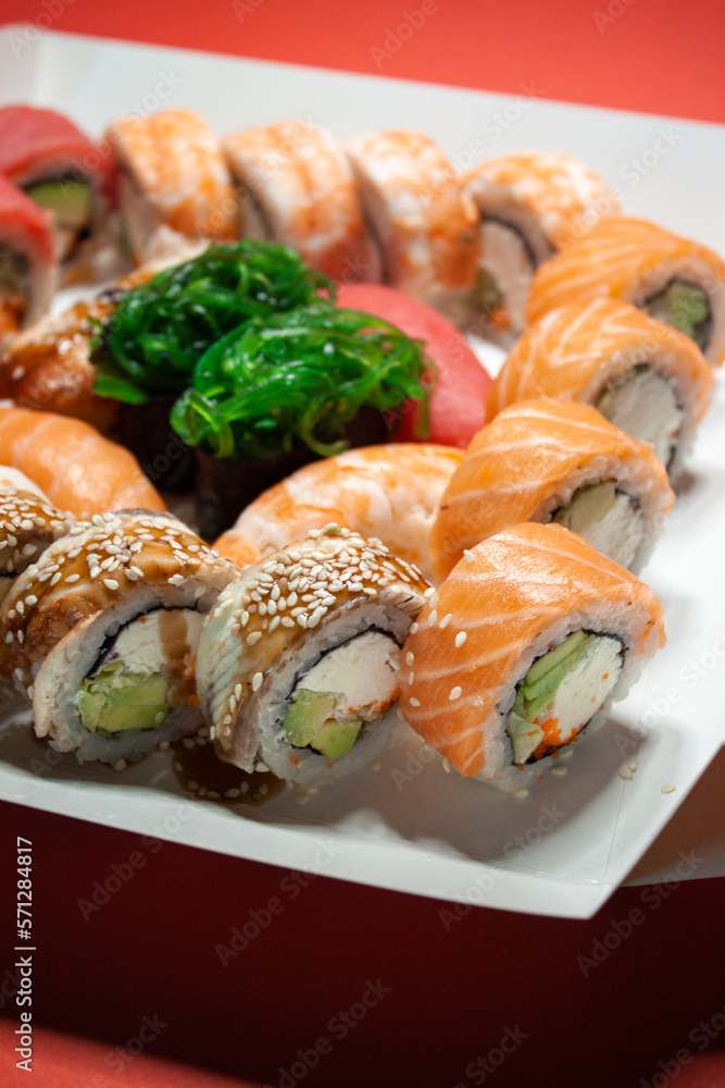 salmon tuna chuka shrimp eel nigiri gunkan sushi rolls set in white box on red background salmon tuna chuka shrimp eel nigiri gunkan sushi rolls set in white box on red background