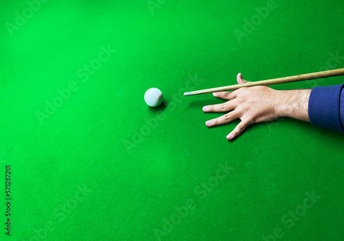 Man hitting a white ball on a snooker table with a green backdrop and empty copy space. Snooker table background