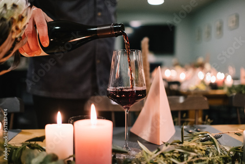 Kellner schenkt Rotwein in ein Weinglas (ID: 571287474)