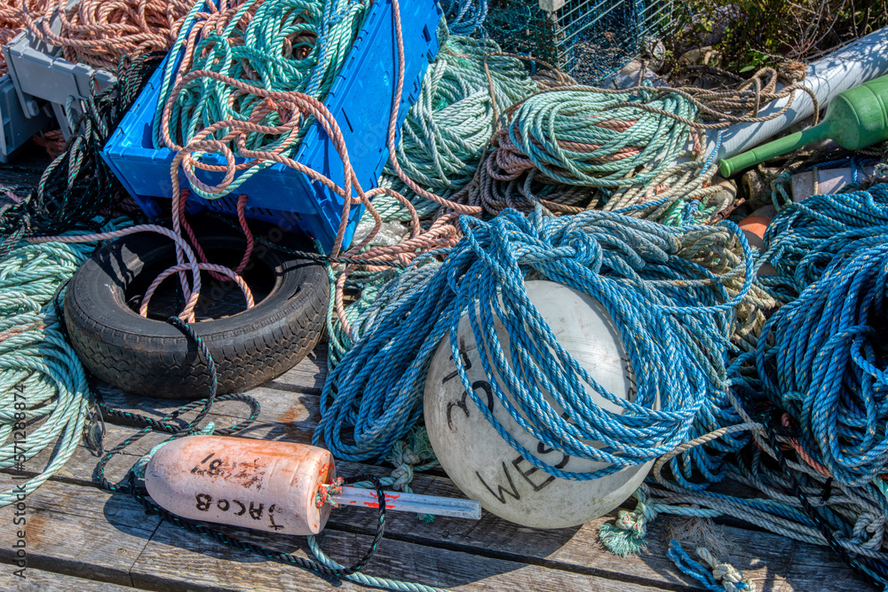 Colorful ropes and lobster buoys stacked up on a weathered fishing pier in Maine.