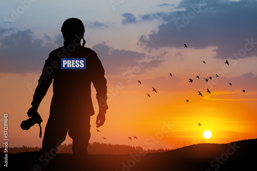 Photojournalist silhouette documenting war or conflict. Photojournalist at sunset. War, army, technology and journalist work concept.