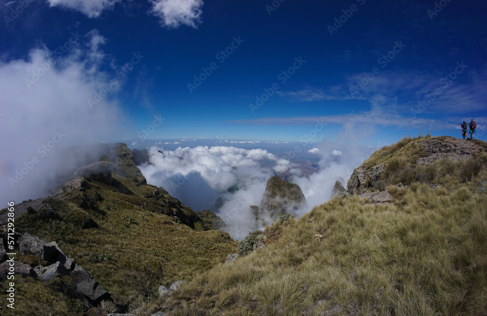 Panoramic view of valley landscape with clouds and a hiker and scout in the distance in the Simien Mountains Ethiopia, Africa