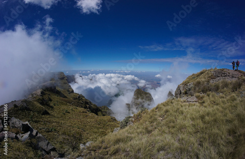 Panoramic view of valley landscape with clouds and a hiker and scout in the distance in the Simien Mountains Ethiopia  Africa
