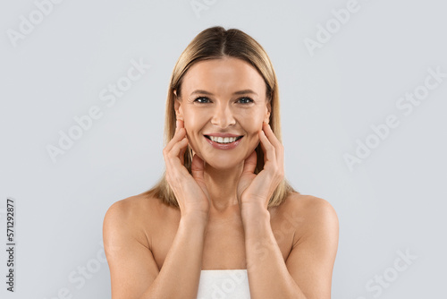 Pretty blonde middle aged woman touching her face