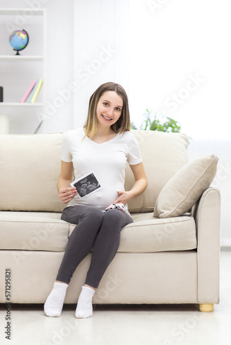 Photo of smiling pregnant woman with ultrasound result.