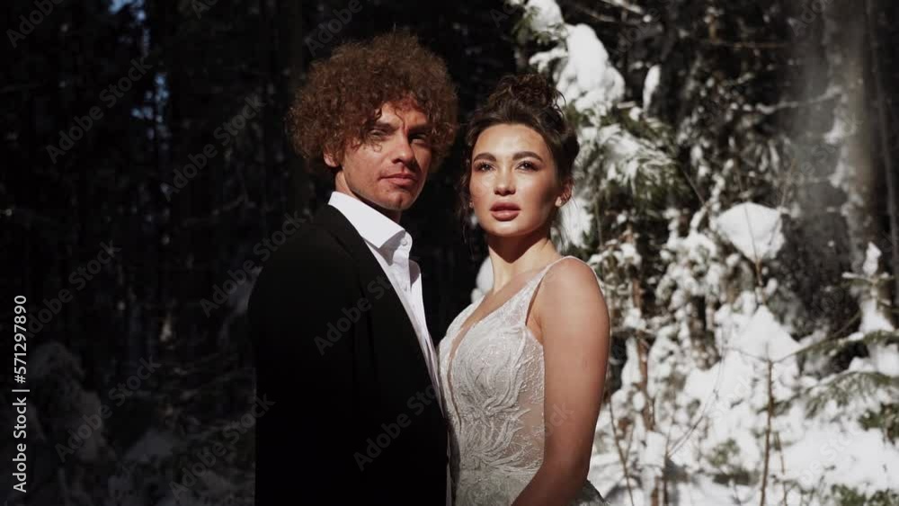 Beautiful wedding couple. Winter wedding in the mountains covered with snow of the groom in a beautiful suit and the bride in a beautiful wedding dress.Сoncept of a winter wedding Beautiful wedding couple. Winter wedding in the mountains covered with snow of the groom in a beautiful suit and the bride in a beautiful wedding dress.Сoncept of a winter wedding