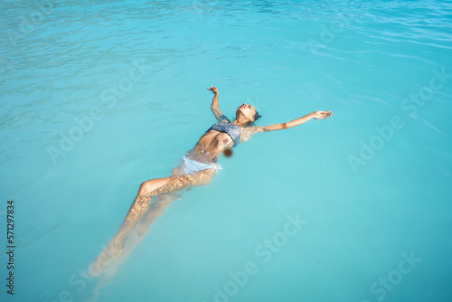 Perfect body woman in swimsuit bikini relaxing in blue ocean water  enjoying her summer vacation  feeling happiness and carefree
