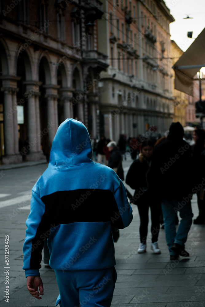 Stylish man with blue hood walking down the streets of Bologna