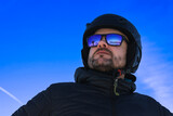 Blue sky and mountains reflected in skier's glasses, skier in the rays of the sun, winter in Italy, winter sports lover, mountains in winter.