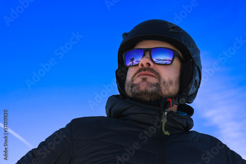 Blue sky and mountains reflected in skier's glasses, skier in the rays of the sun, winter in Italy, winter sports lover, mountains in winter.