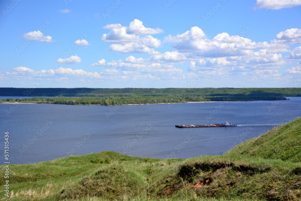 barge with freight on the Volga river with island and cloudy sky, view from top of the hill