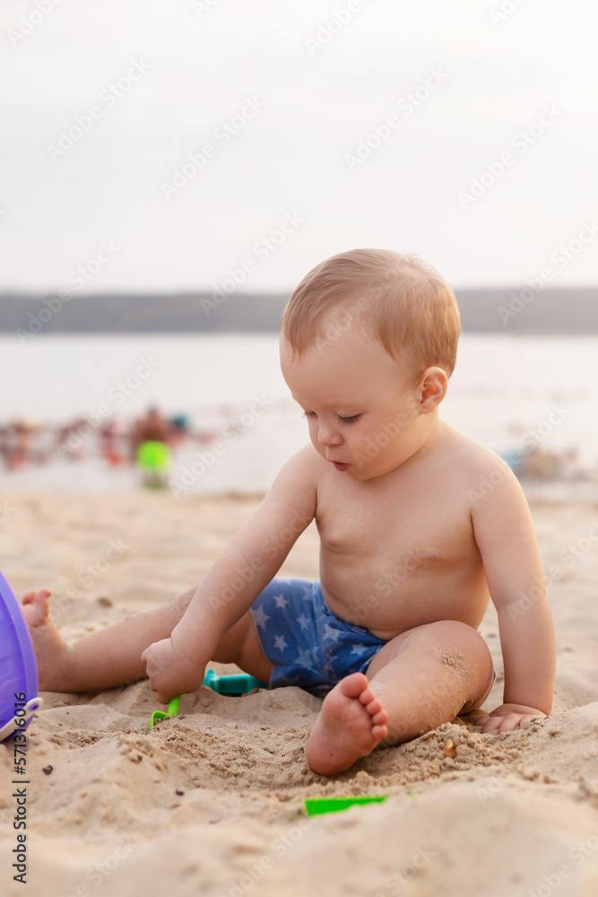 charming toddler sits in the sand and plays with toys on the seashore charming toddler sits in the sand and plays with toys on the seashore
