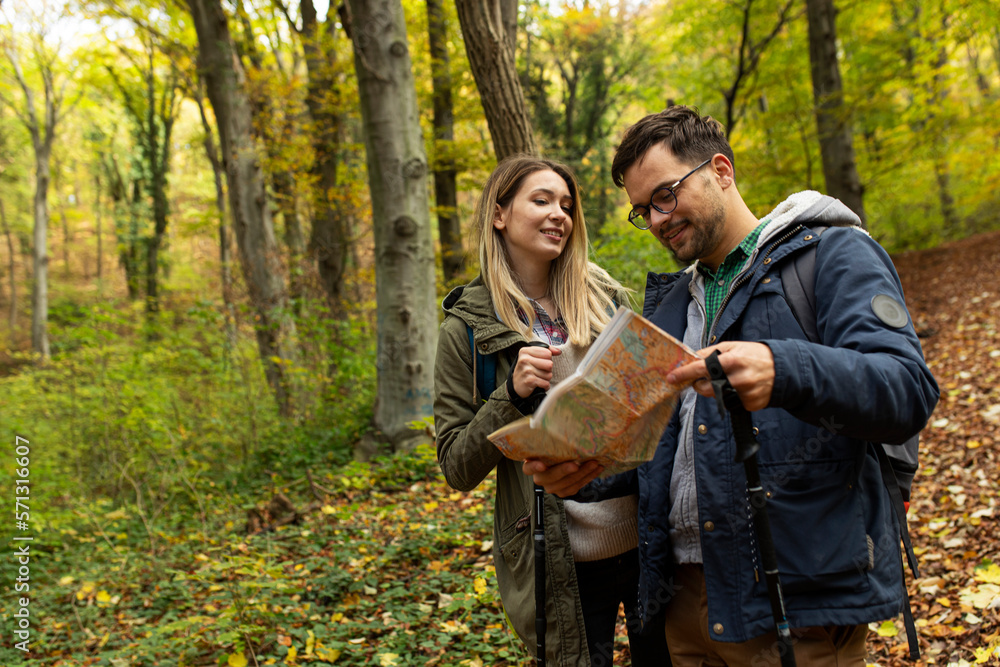 Smiling couple in the forest checking on a map
