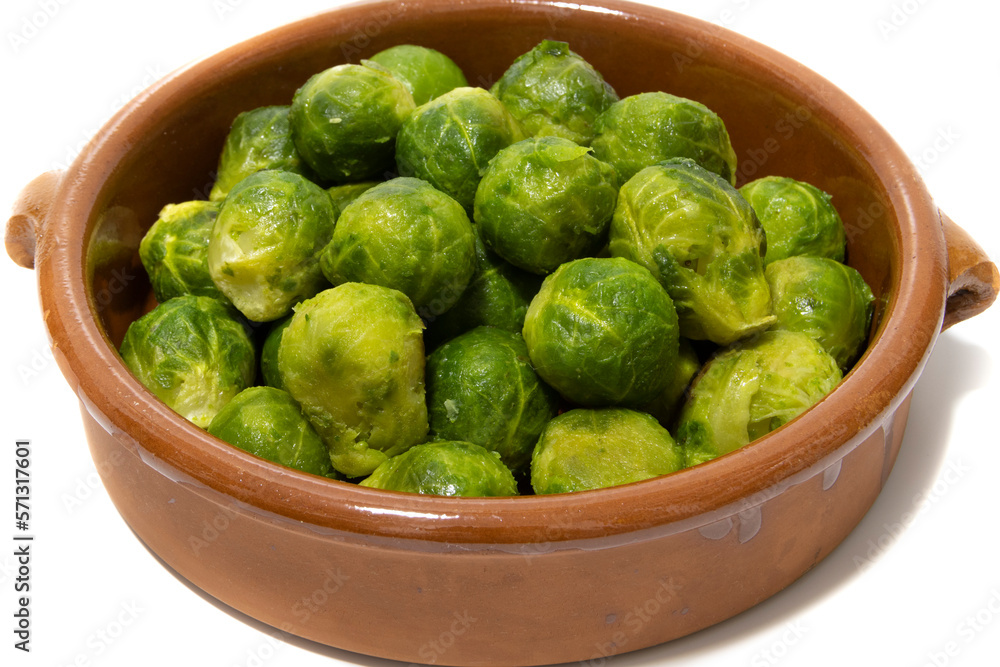 A pile of boiled brussels sprouts, served in a clay bowl. Isolated on a white background. Healthy food concept. A pile of boiled brussels sprouts, served in a clay bowl. Isolated on a white background. Healthy food concept.