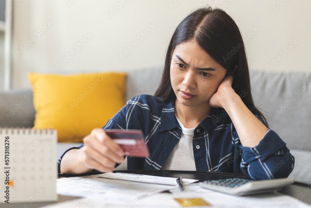 Business financial concept, stressed asian young business woman hand holding credit card for calculate accounting expense of bill, tax for payment on due deadline, trying to find money to pay debt.