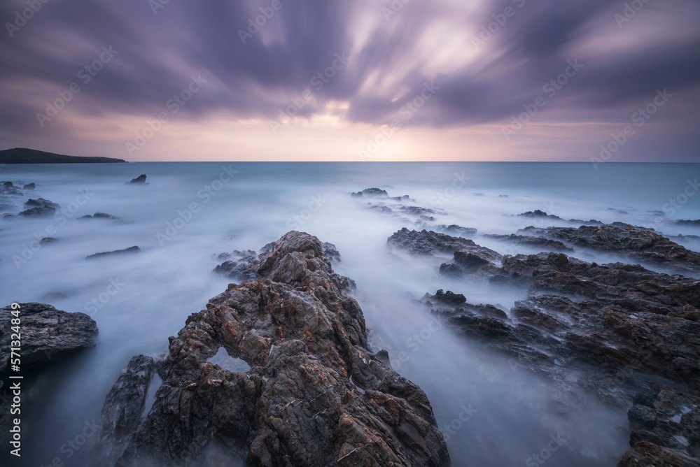 Long exposure shot of rocks on seaside, blurred and foggy sea water and clouds on sky Long exposure shot of rocks on seaside, blurred and foggy sea water and clouds on sky