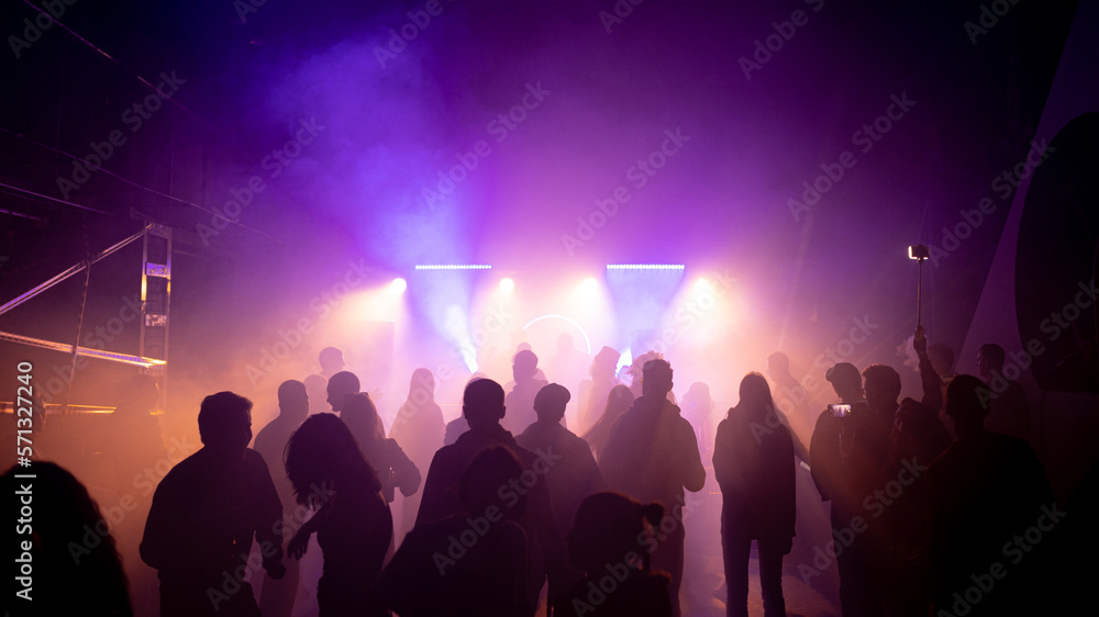Obraz premium MOSCOW, Russia - February 2, 2023:Crowd dancing on a techno rave, streaming bright lights in a nightclub, cheerful vibe