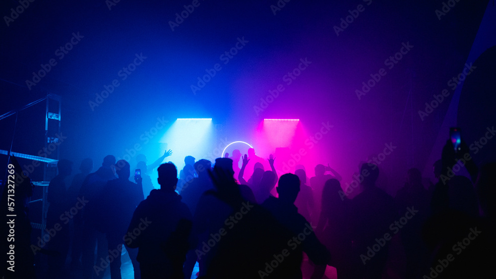 MOSCOW, Russia - February 2, 2023:Huge rave crowd in deemed bright lights on a nightclub, view from aside