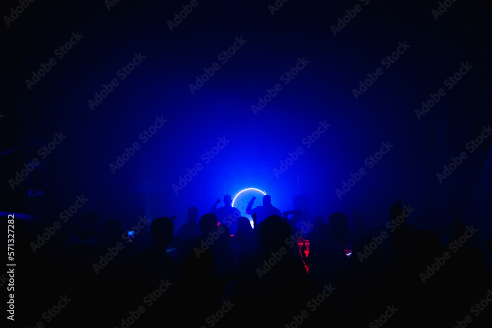 MOSCOW, Russia - February 2, 2023:Huge rave crowd in deemed bright lights on a nightclub, view from aside MOSCOW, Russia - February 2, 2023:Huge rave crowd in deemed bright lights on a nightclub, view from aside