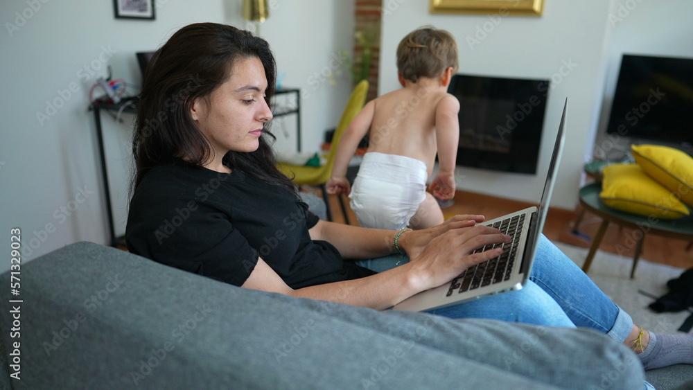 Woman working from home using laptop with child jumping from sofa. Parent in front of computer screen browsing internet online multi tasking Woman working from home using laptop with child jumping from sofa. Parent in front of computer screen browsing internet online multi tasking