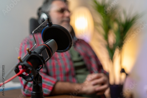 man host streaming podcast with condenser microphone work on laptop at small broadcast home studio
