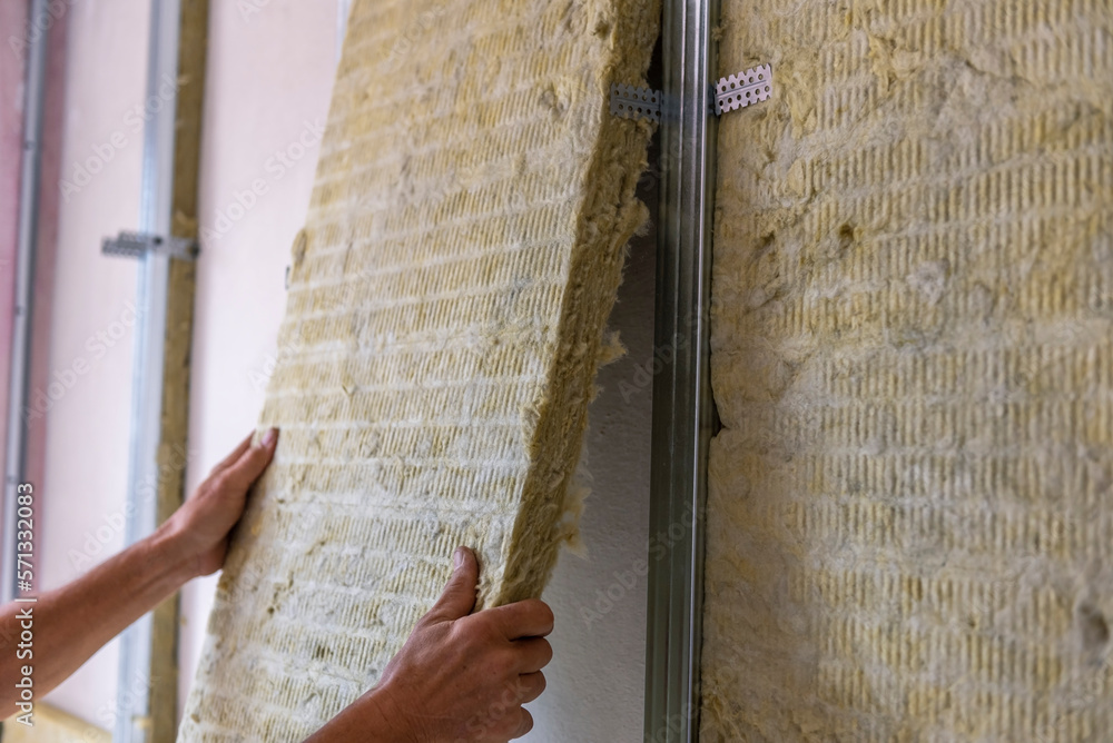 Worker insulating a room wall with mineral rock wool thermal insulation. - obrazy, fototapety, plakaty 