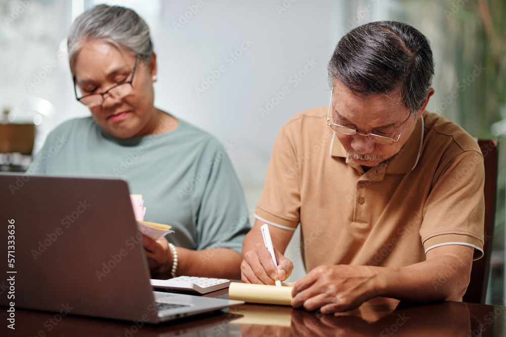 Senior couple busy with home bookkeeping, planning expenses and investment Senior couple busy with home bookkeeping, planning expenses and investment