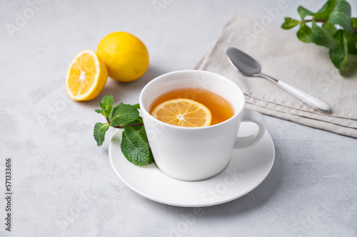 A cup of tea with lemon and mint on a light background. The concept of a healthy breakfast drink