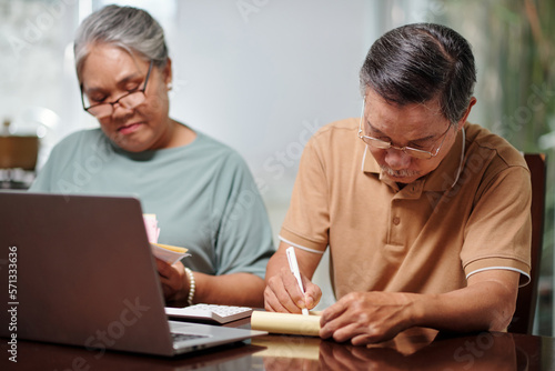 Senior couple busy with home bookkeeping, planning expenses and investment