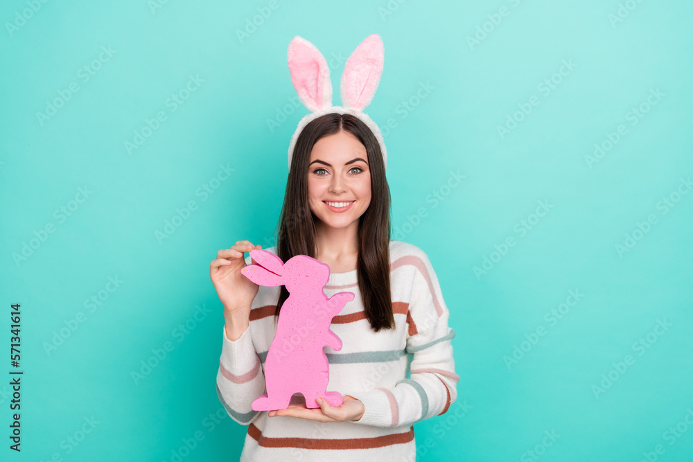 Photo of charming cheerful lady hold rabbit figure wear bunny ears striped pullover isolated blue color background Photo of charming cheerful lady hold rabbit figure wear bunny ears striped pullover isolated blue color background