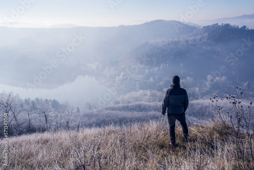 hiking man on the hilltop in the morning, a lake and hills in the background © Tamas