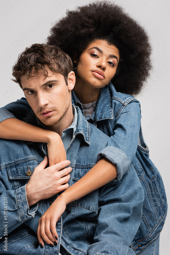 Obraz premium brunette african american model looking at camera and hugging stylish man isolated on grey.