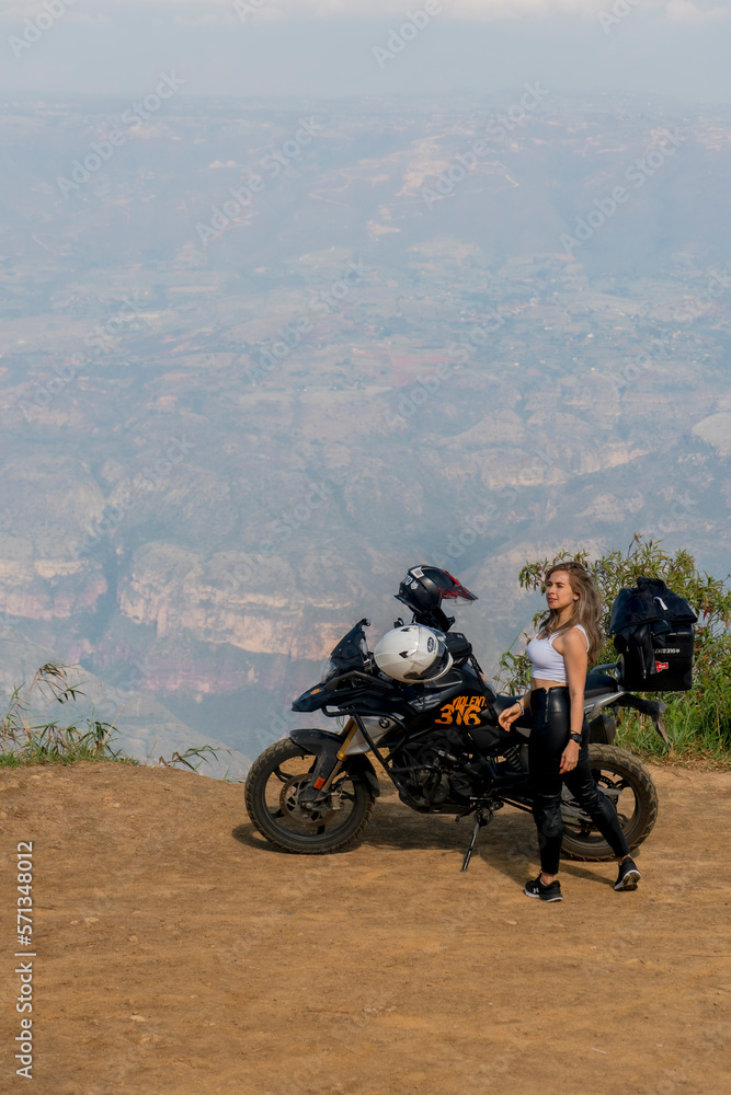 Obraz premium Beautiful blonde woman traveling by motorcycle through old towns walking and walking through its streets and mountains full of gardens enjoying the beautiful views and landscapes on vacation