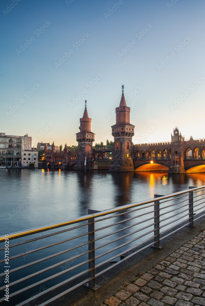 Berliner Oberbaumbrücke am Abend nach Sonnenuntergang. Langzeitbelichtung der Spree und der berühmten Brücke von Friedrichshain nach Kreuzberg mit Nachtlichtern und Spiegelungen im Wasser.