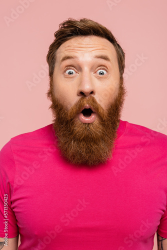 amazed bearded man with open mouth looking at camera isolated on pink. © LIGHTFIELD STUDIOS