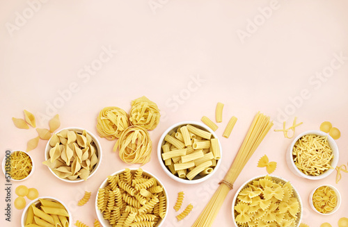 Mix of pasta shapes varieties on pink background: penne and fusilli, farfalle and macaroni, rigatoni and rotini, rigate and conchiglie 
