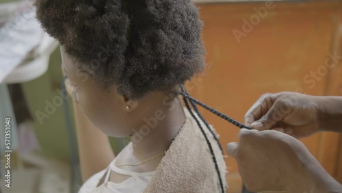 Black woman braiding her hair outdoors