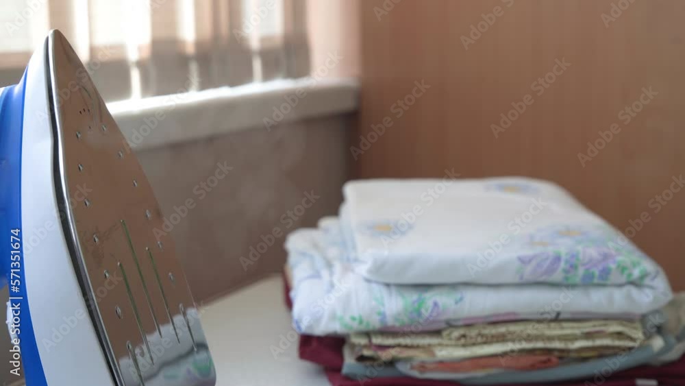 A hot iron is on the table, next to it lies a pile of clean, ironed linen. A hot iron is on the table, next to it lies a pile of clean, ironed linen.