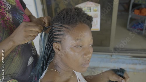 Black woman braiding her hair outdoors