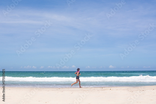 FLORIANOPOLIS, BRAZIL - JANUARY 22, 2023 : a girl runs along the beach Barra da lagoa, Florianopolis, Brazil