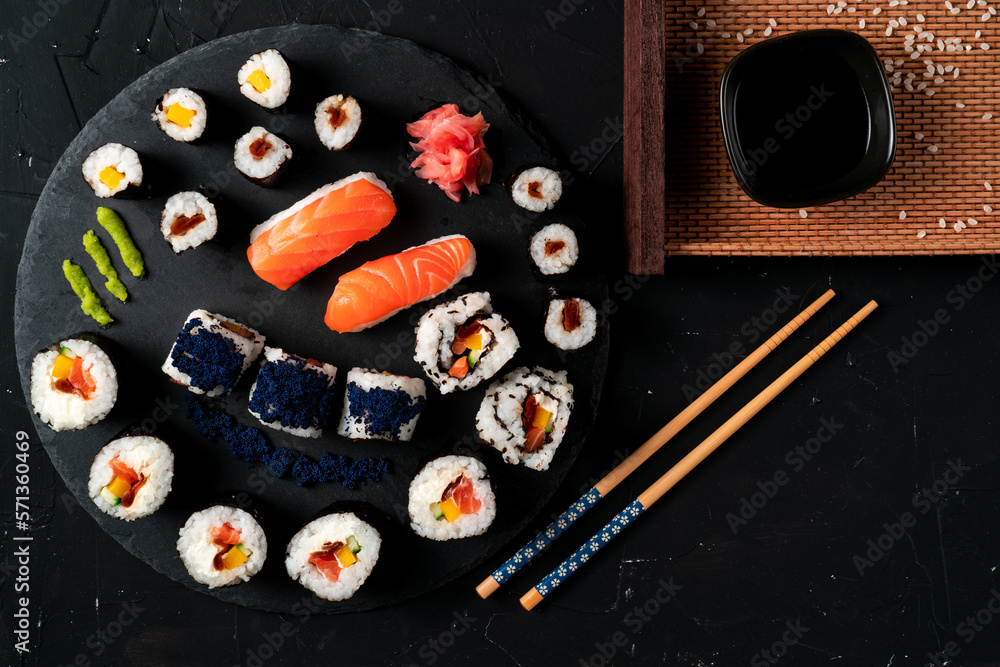 Sushi, traditional Japanese food, served on black stone slate, Nigiri, Maki, futomaki, American roll. 